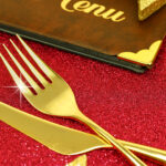 Christmas golden cutlery and restaurant menu on festive background